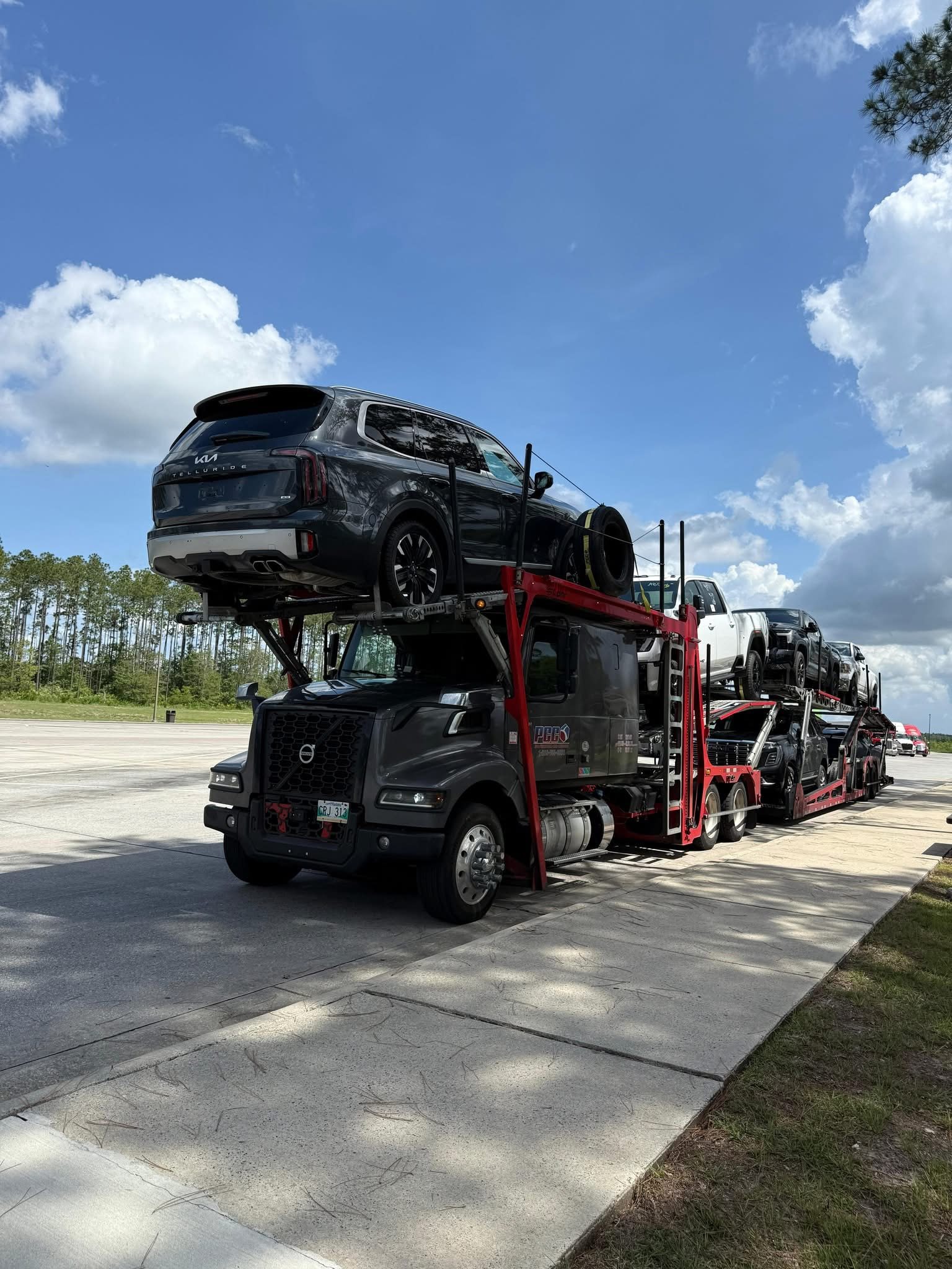 A car carrier loaded with SUVs and trucks under a clear blue sky