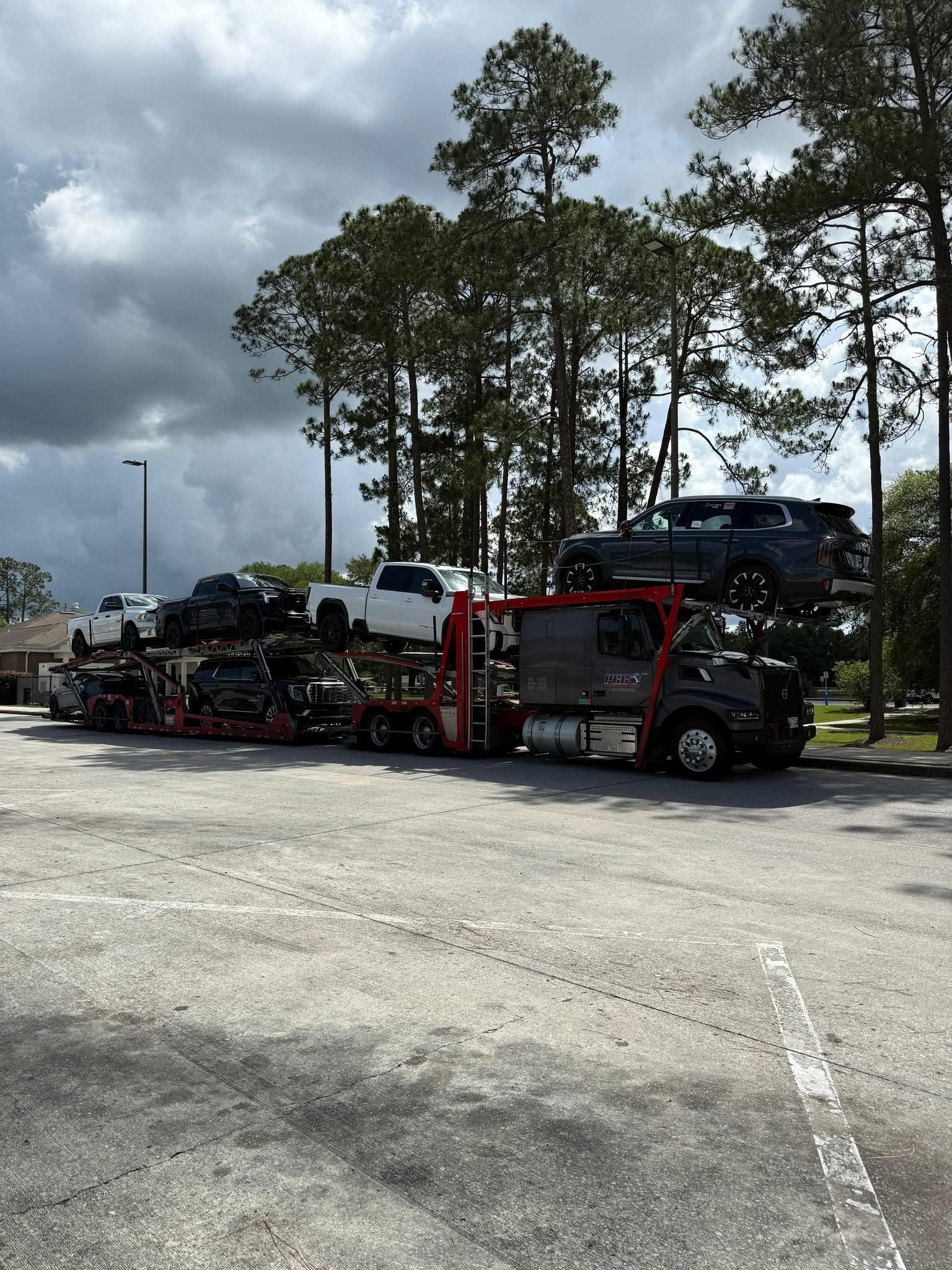 A car carrier loaded with pickup trucks under an overcast sky